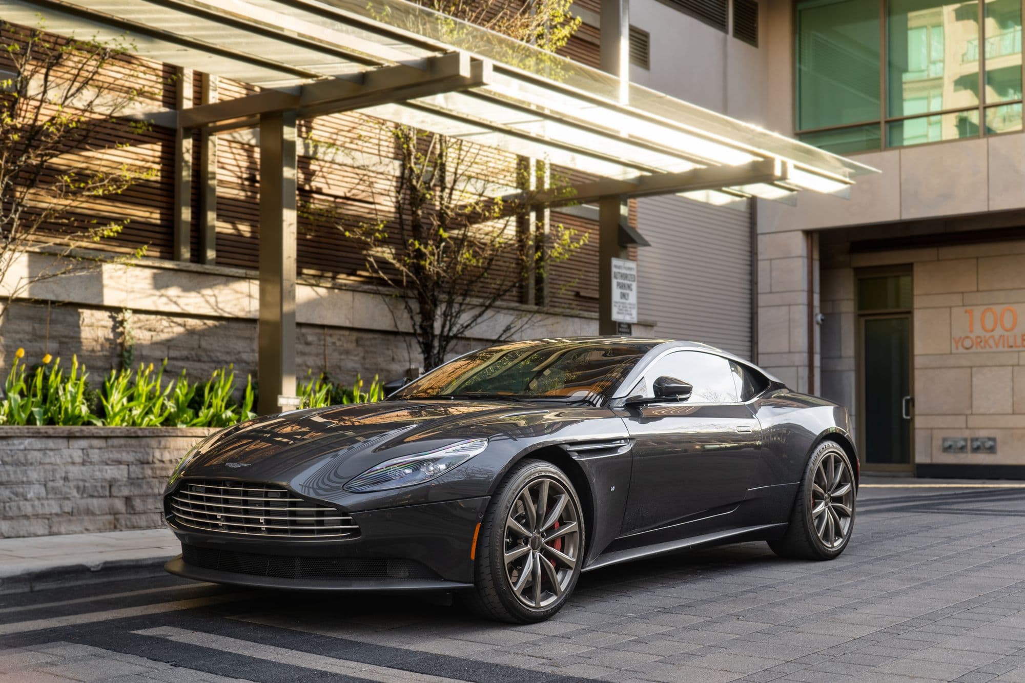 Dark grey Aston Martin DB11 parked outside a modern building