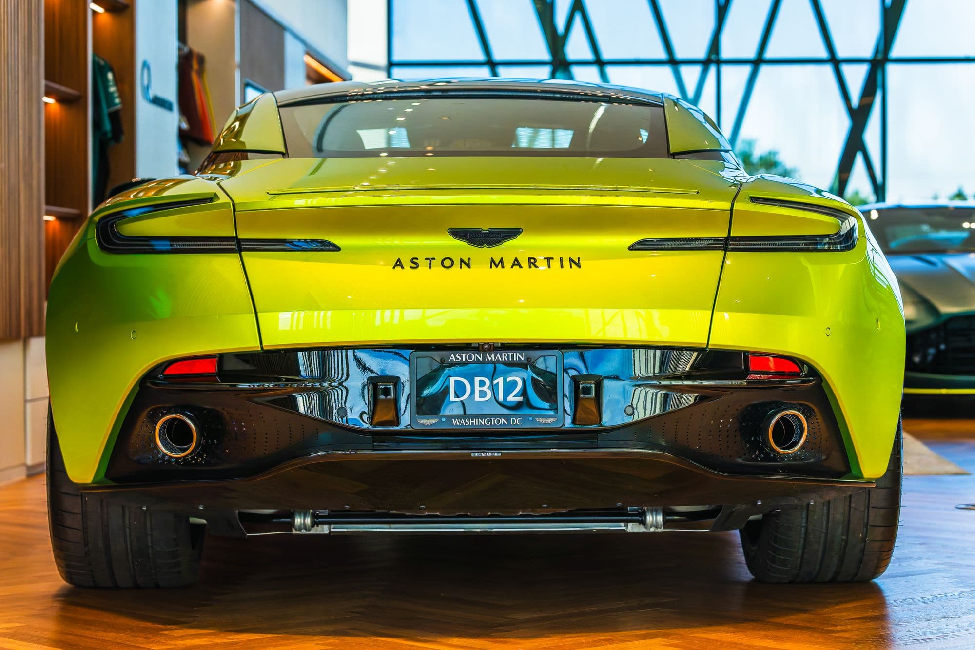 Lime green Aston Martin DB12 displayed in a dealership showroom