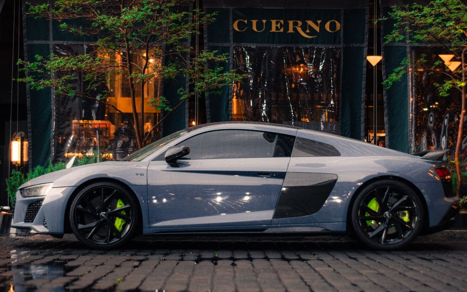 Nardo grey Audi R8 V10 coupe on a wet cobblestone street at night