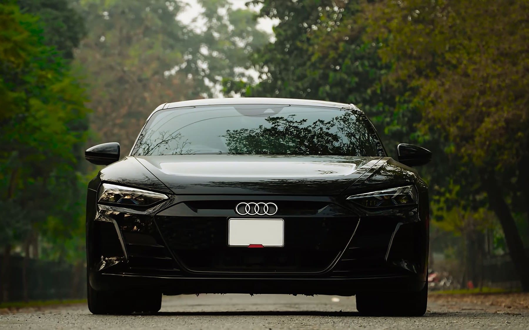 Black Audi e-tron GT electric car on a tree-lined road