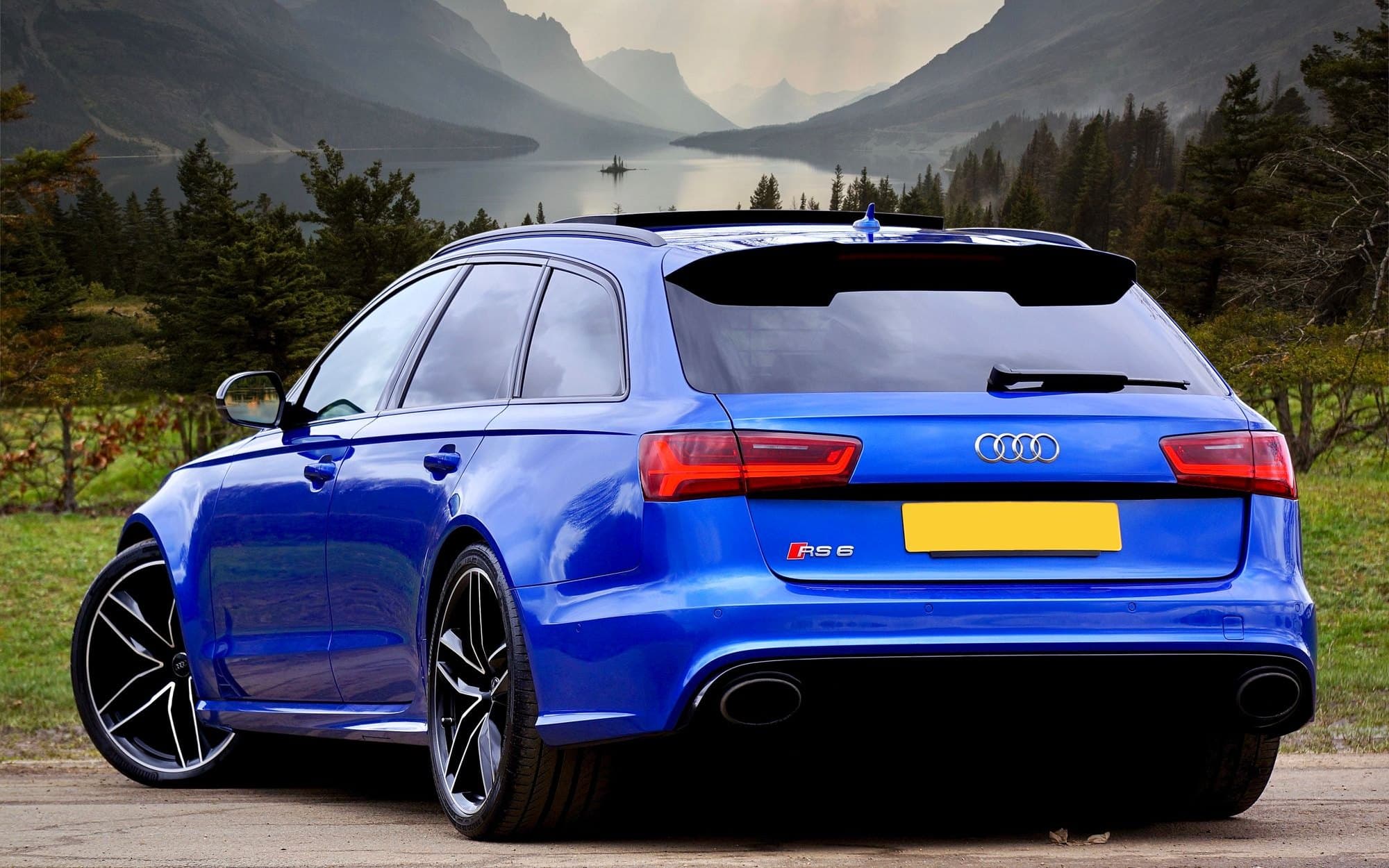 Blue Audi RS6 Avant performance wagon parked before a mountain lake