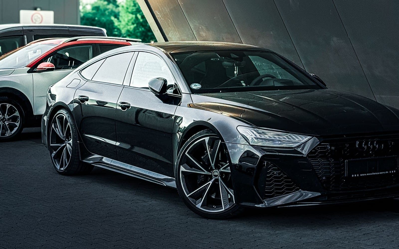 Black Audi RS7 Sportback parked beside angular modern architecture