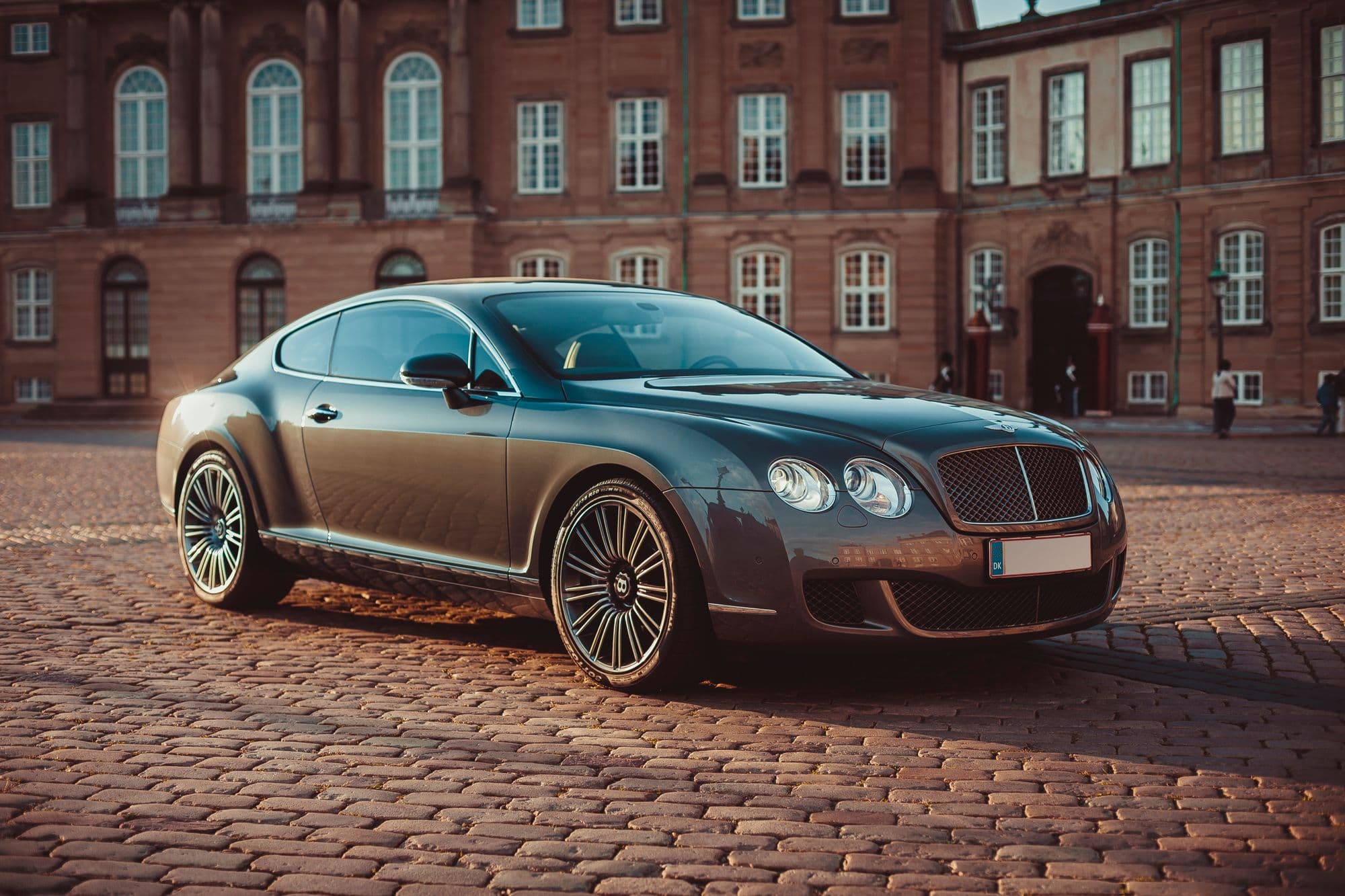 Bentley Continental GT parked on a cobblestone square at sunset