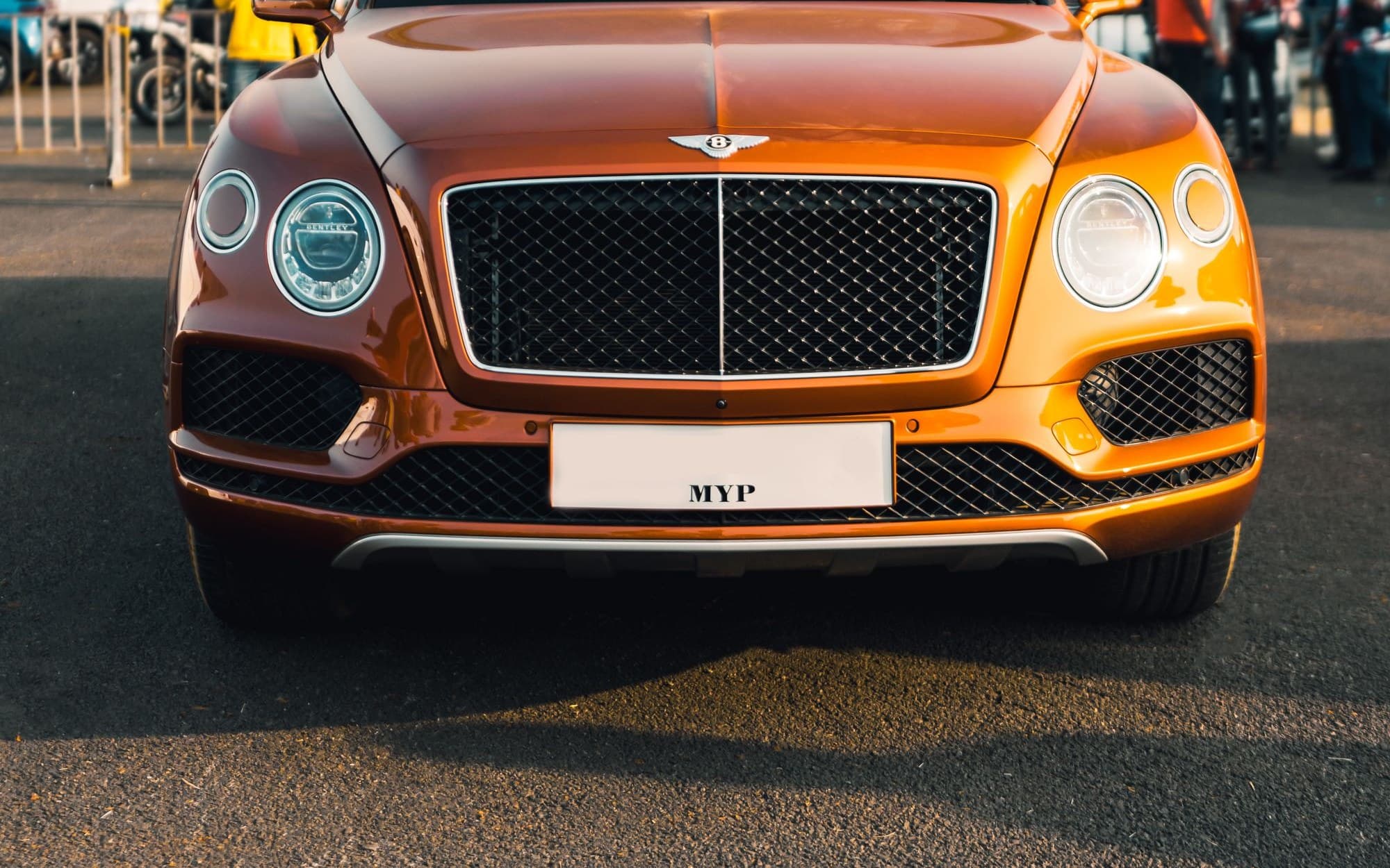 Orange Bentley Bentayga parked at an outdoor car event