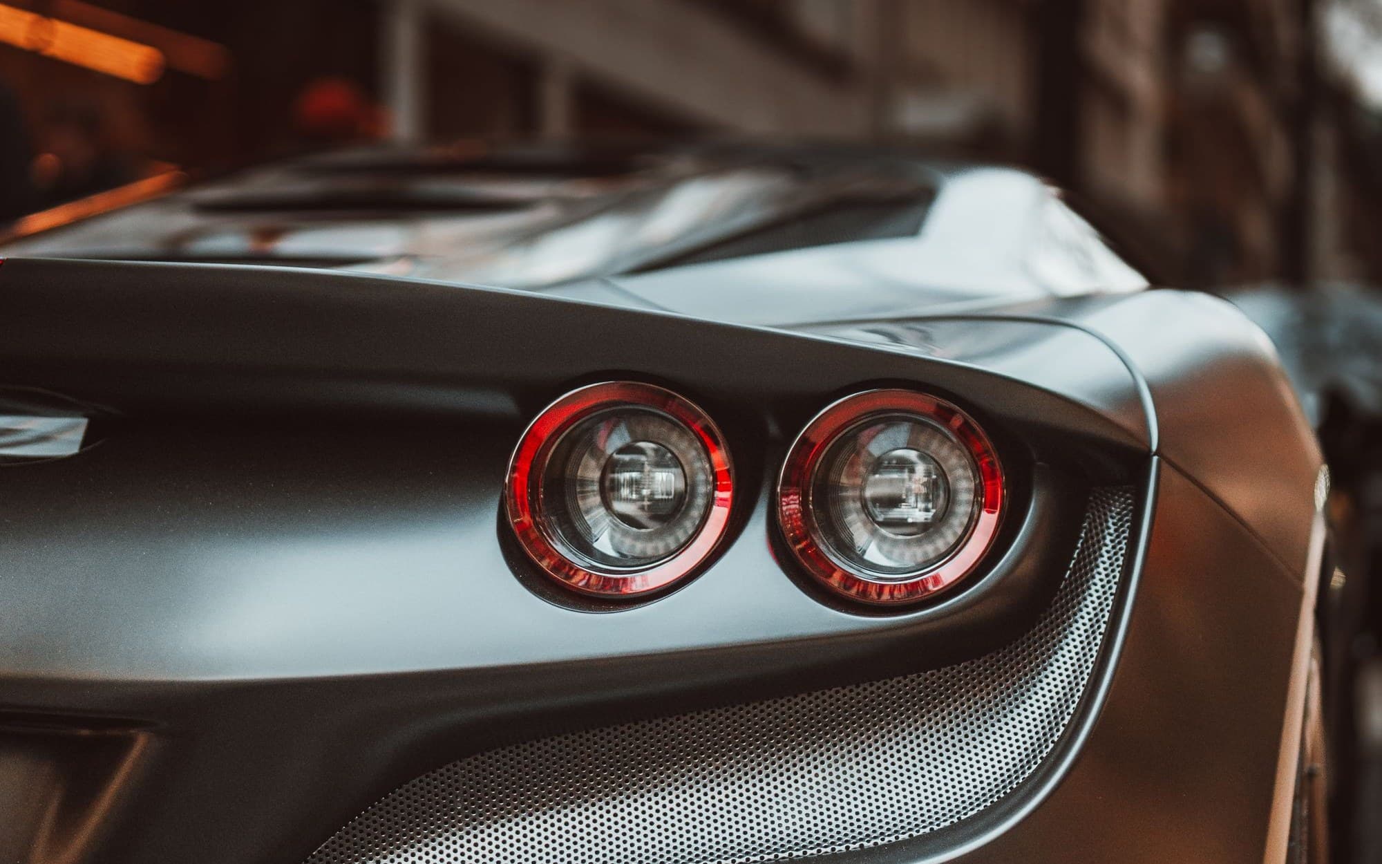 Rear taillights and exhaust of a matte grey Ferrari F8 Tributo on a city street
