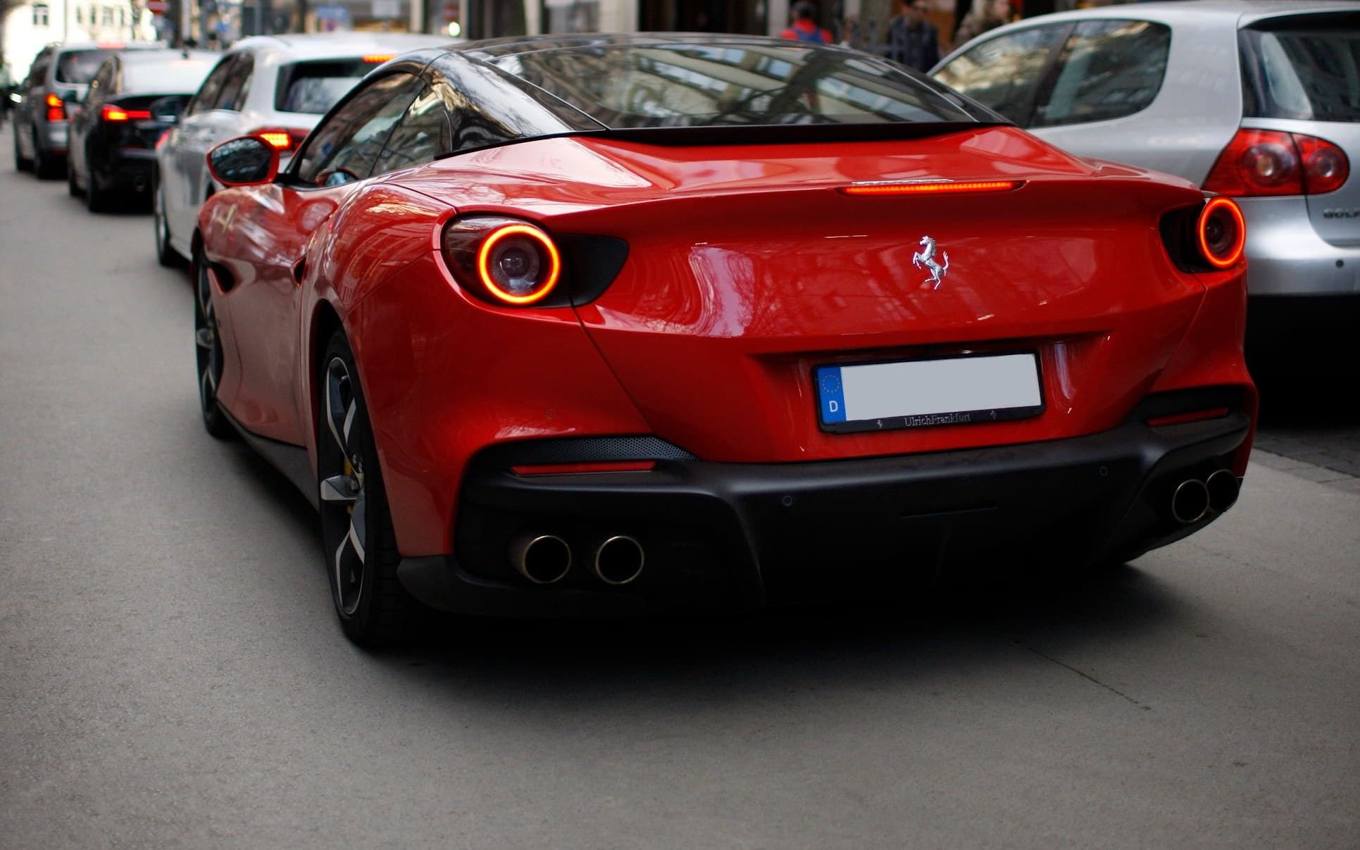 Red Ferrari Portofino driving along a luxury shopping street