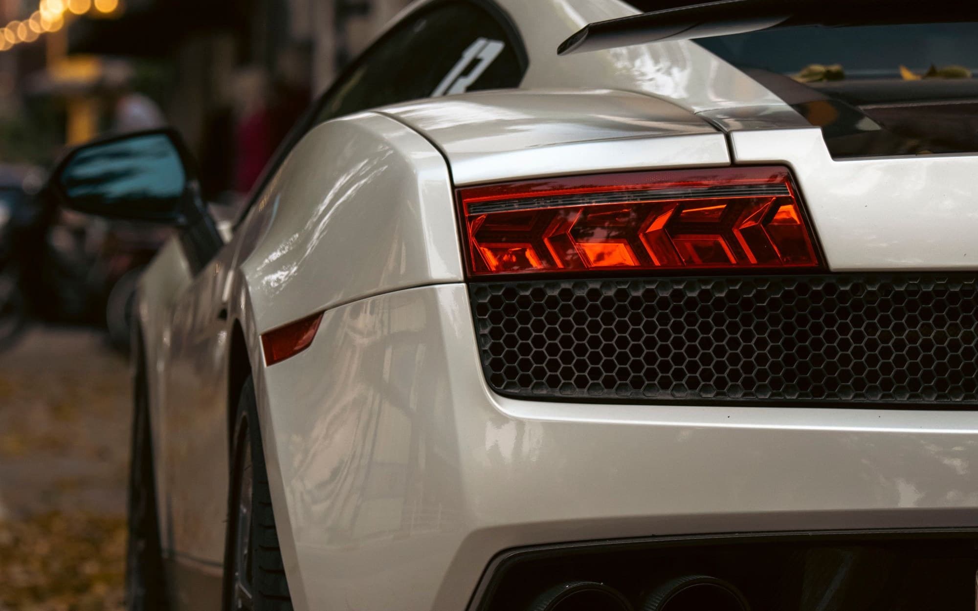 Rear view of a white Lamborghini Gallardo parked on a leaf-strewn street