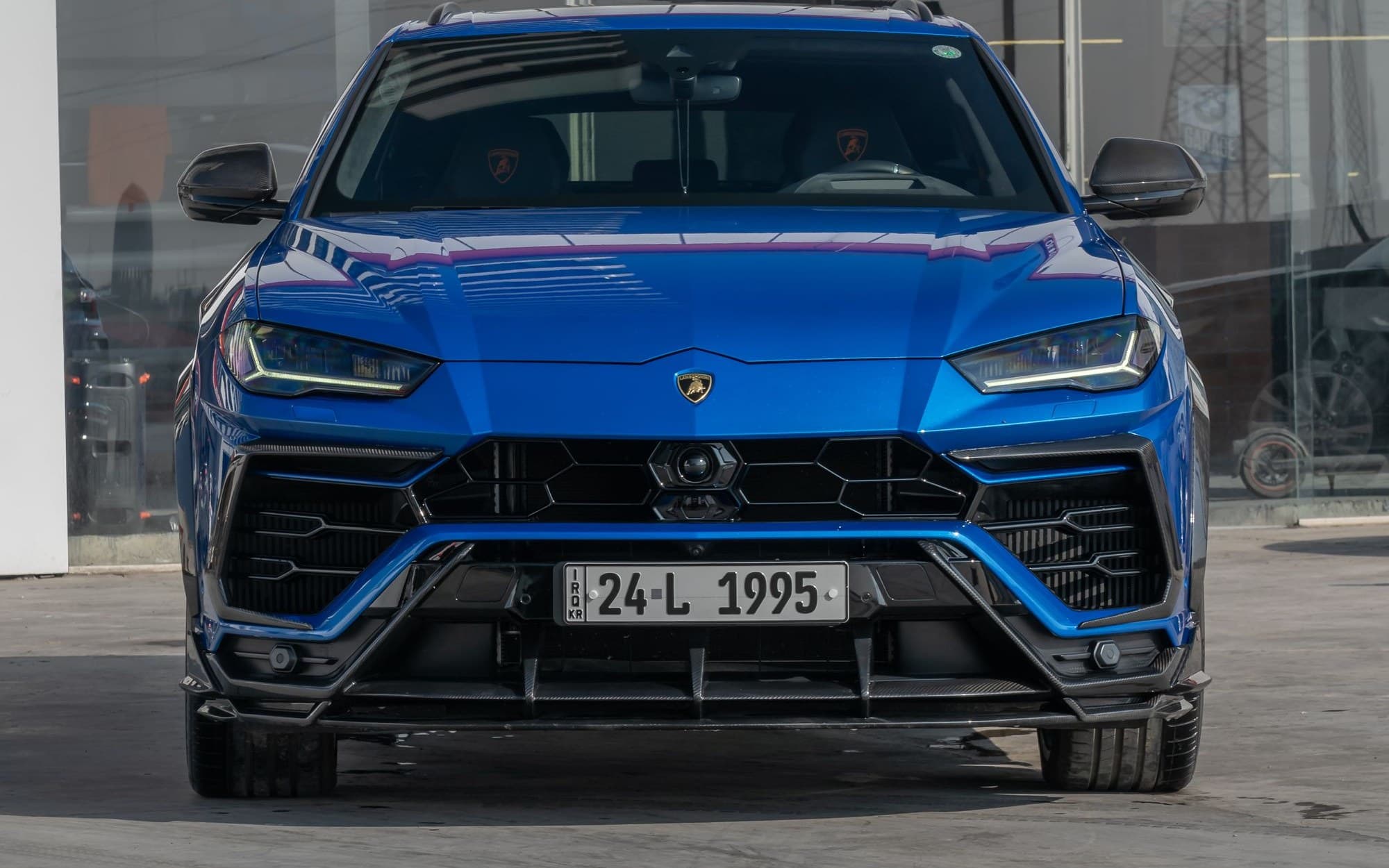 Front view of a blue Lamborghini Urus parked outside a showroom
