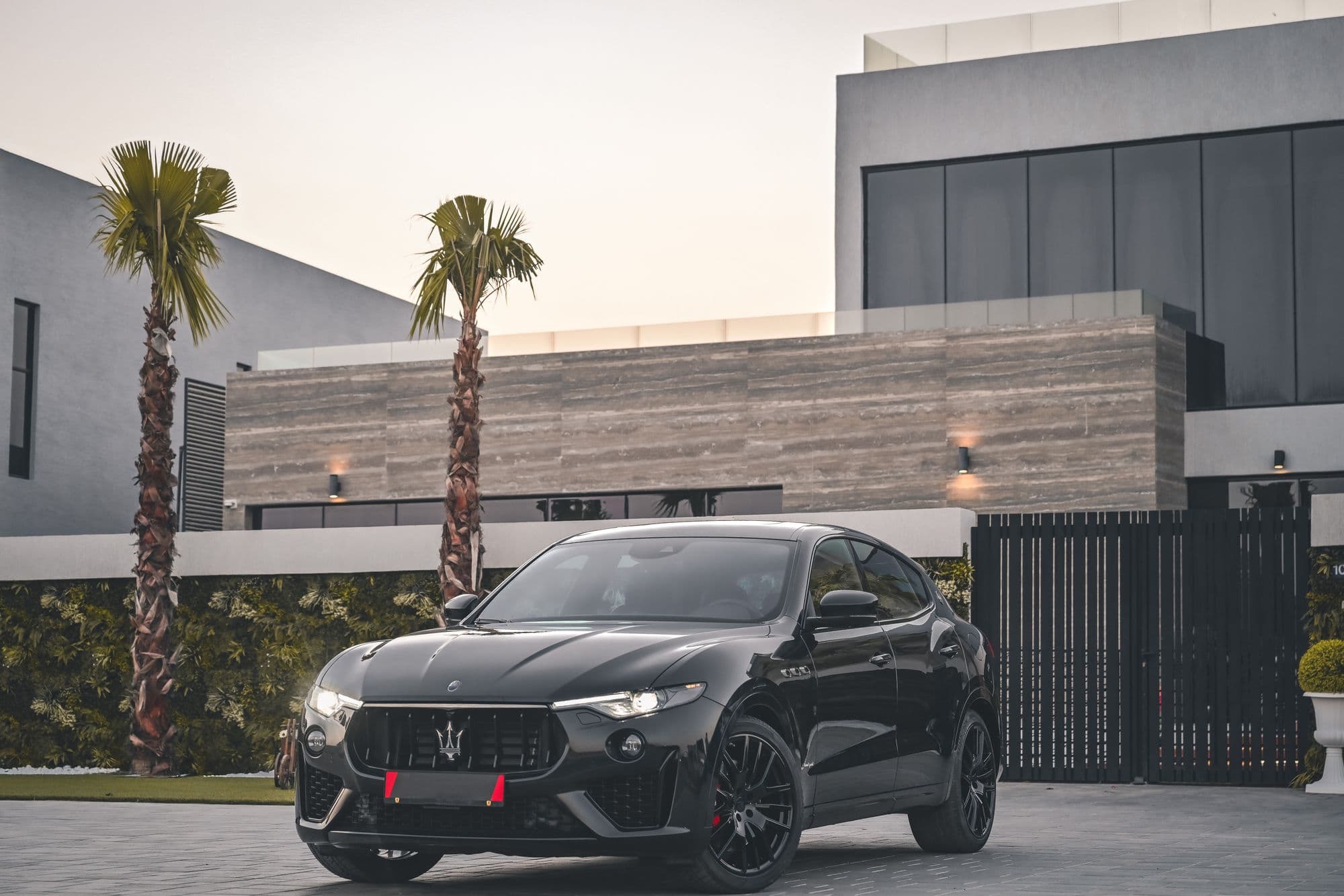 Black Maserati Levante parked in front of a modern villa at dusk