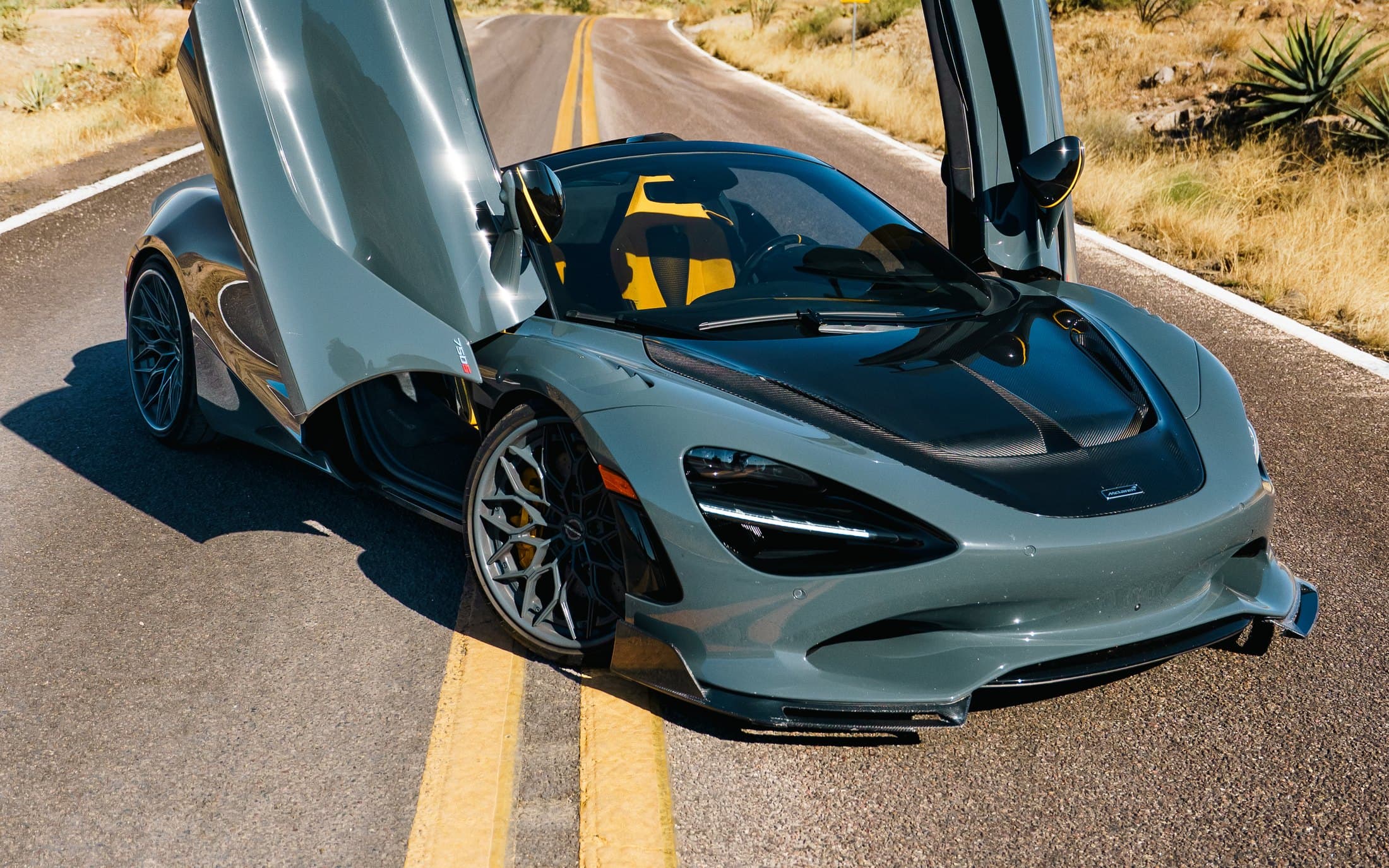 Grey McLaren 750S with its doors raised on a desert highway