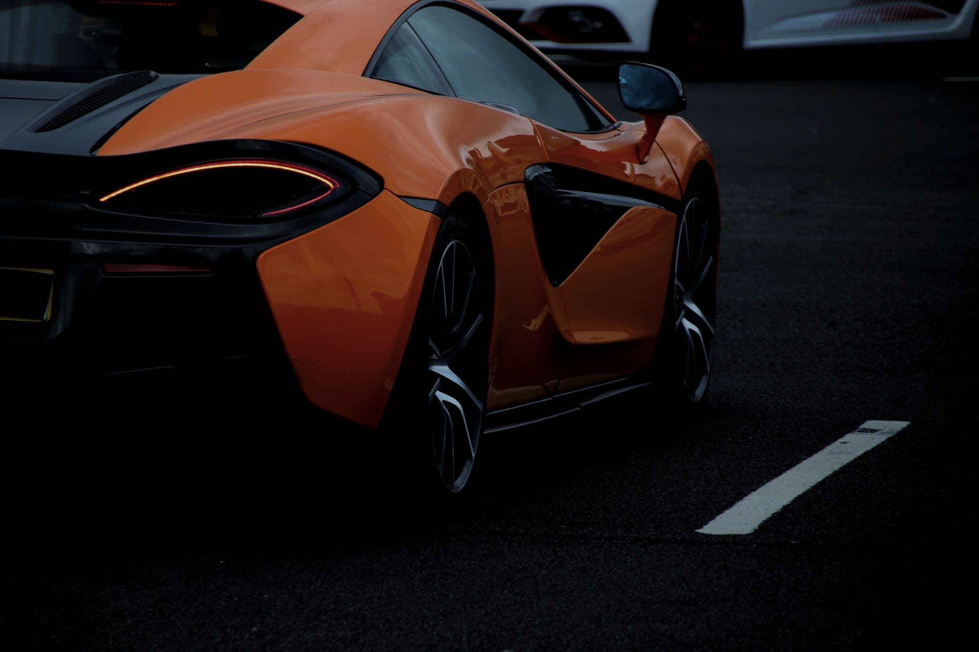 Orange McLaren 570S parked in a dark lot at dusk