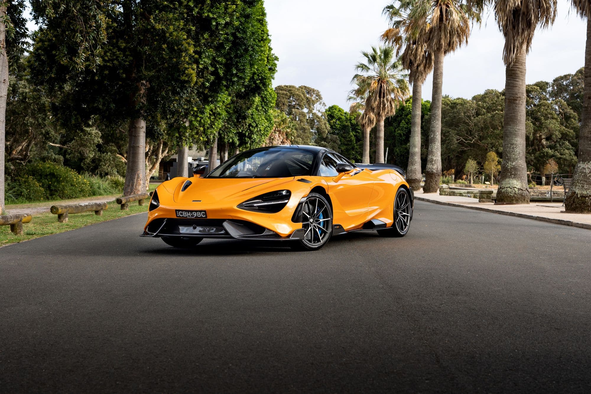 Orange McLaren 765LT parked on a palm-lined road