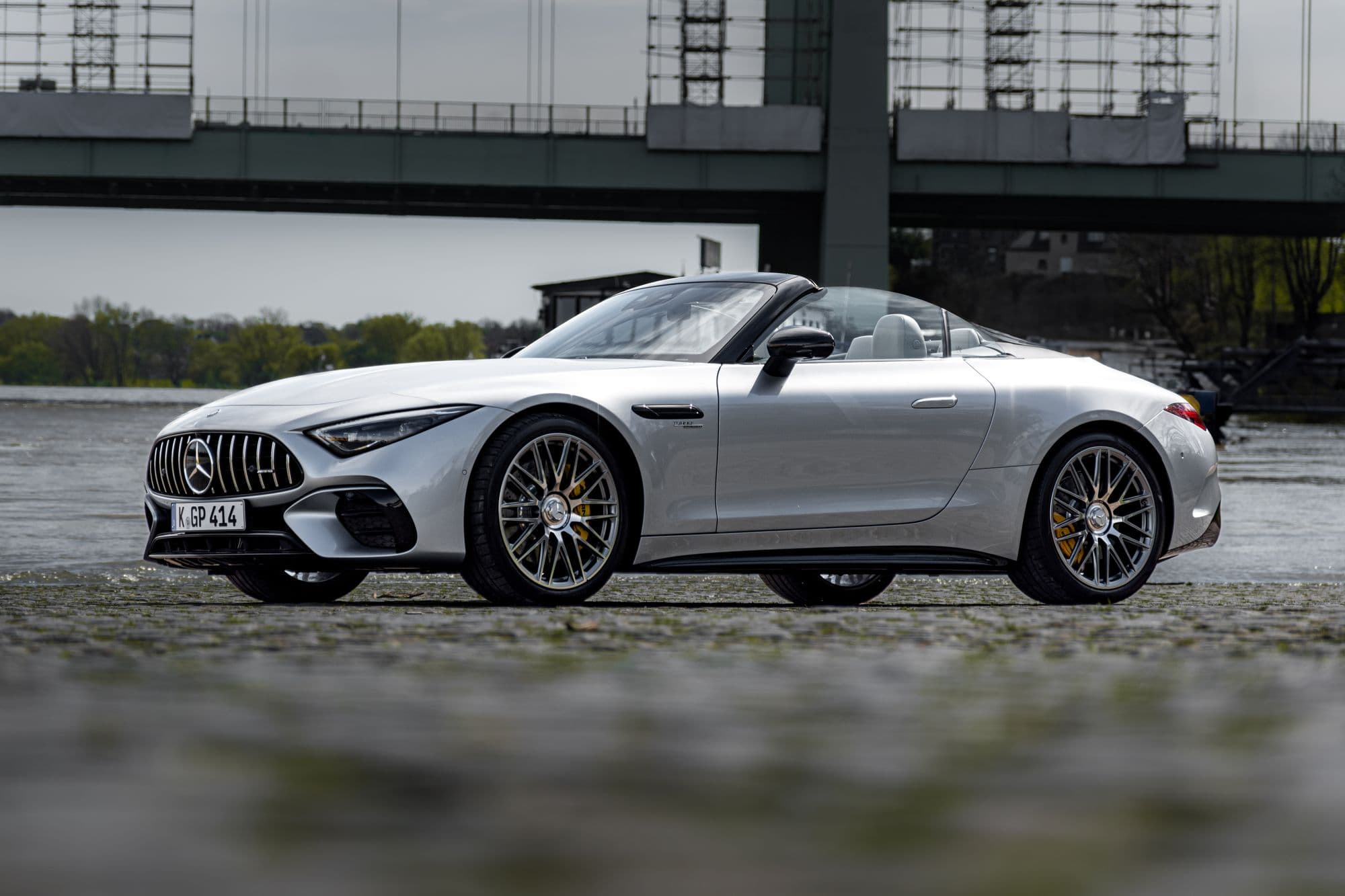Silver Mercedes-AMG SL roadster parked on a riverside promenade