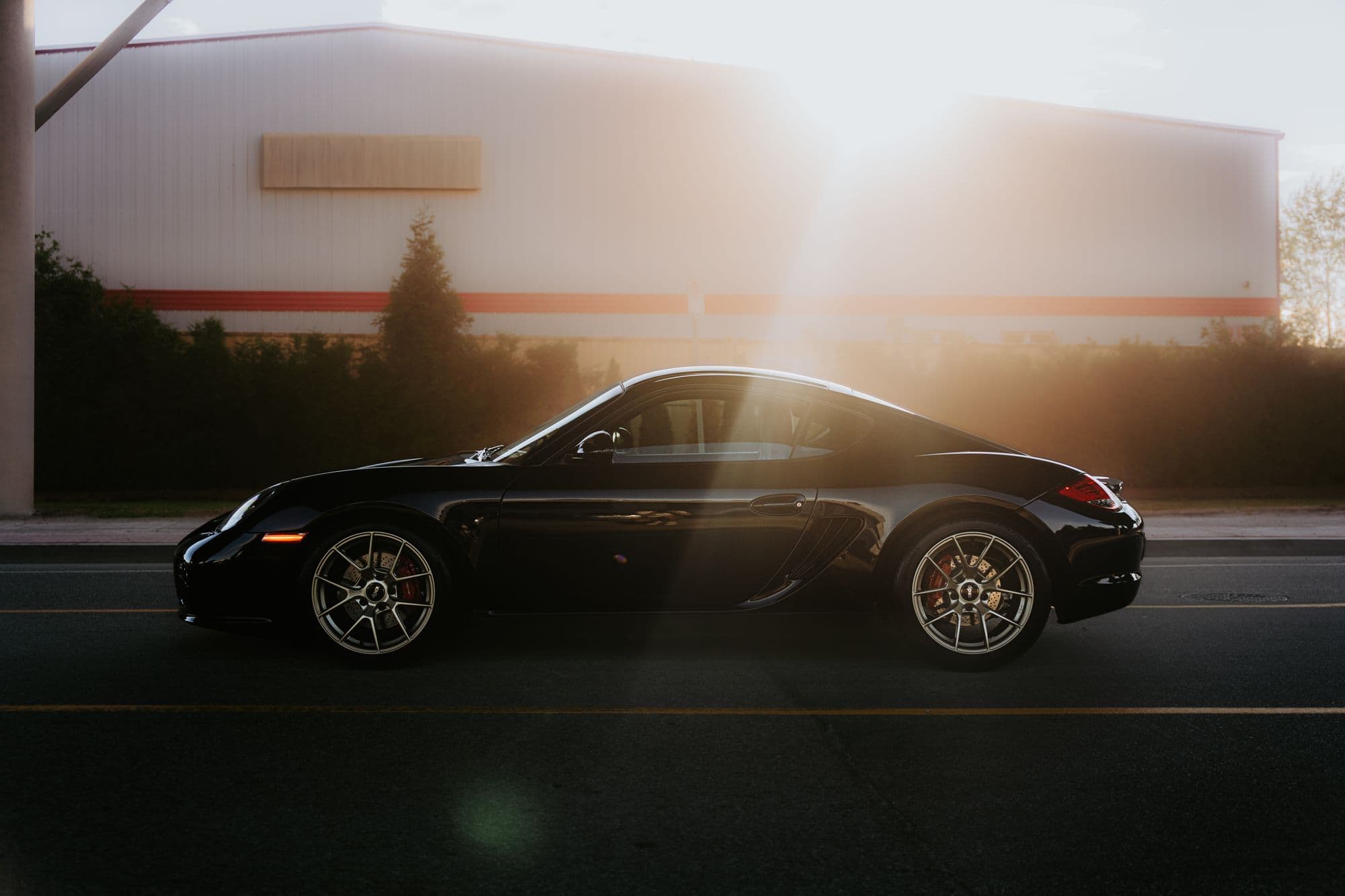 Black Porsche sports coupe in profile lit by warm evening sun
