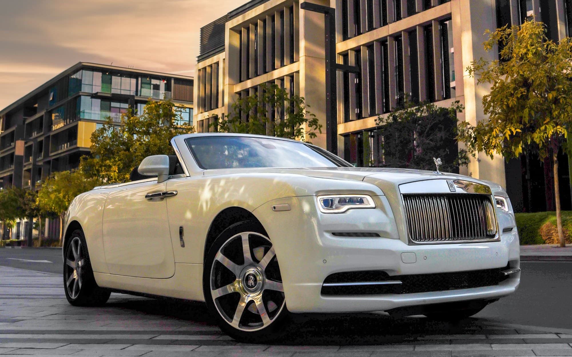 White Rolls-Royce Dawn convertible with the top down in a modern city district